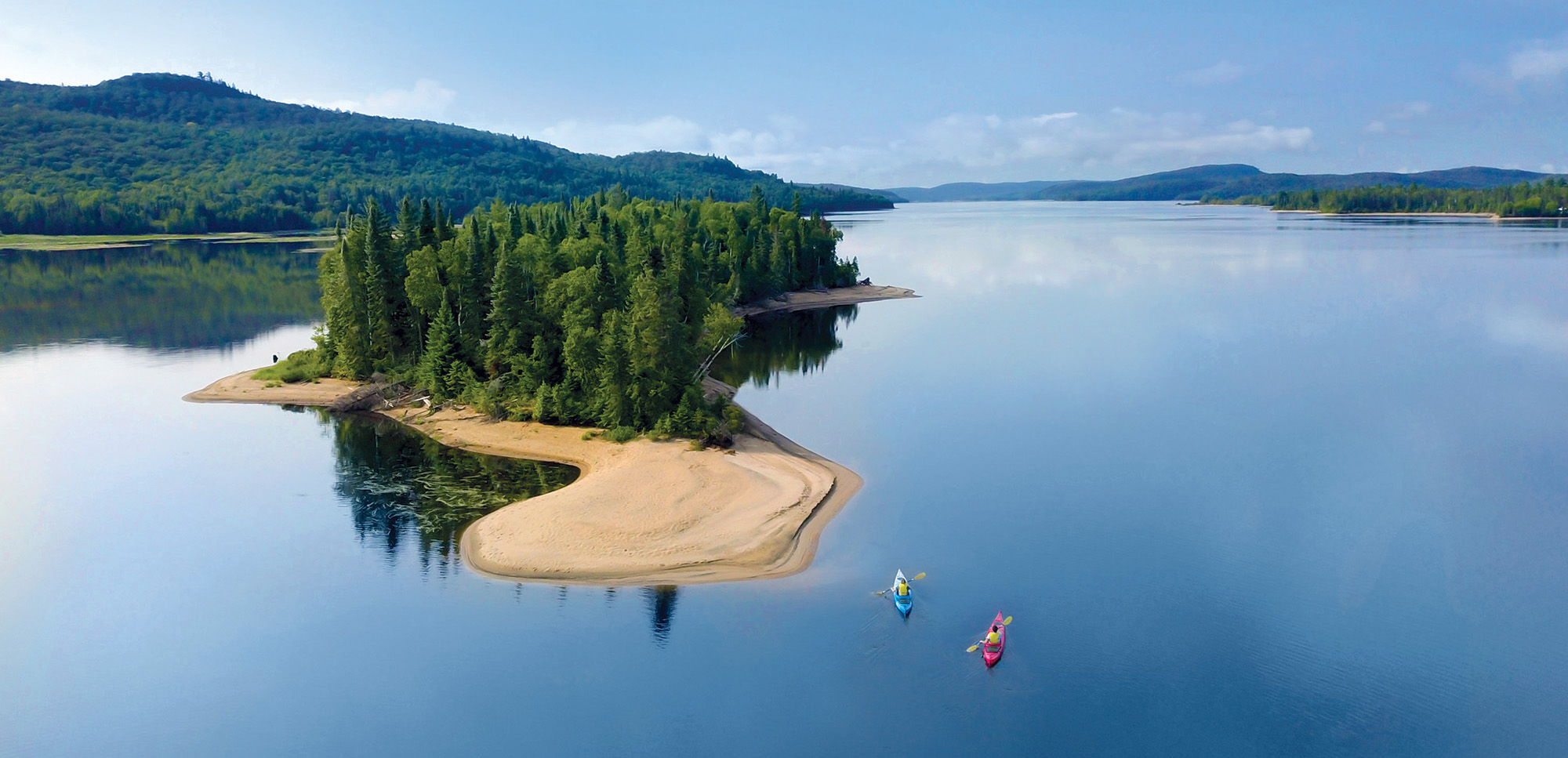 Vue panoramique d'un lac dans les Laurentides, où deux personnes font du Kayak.
