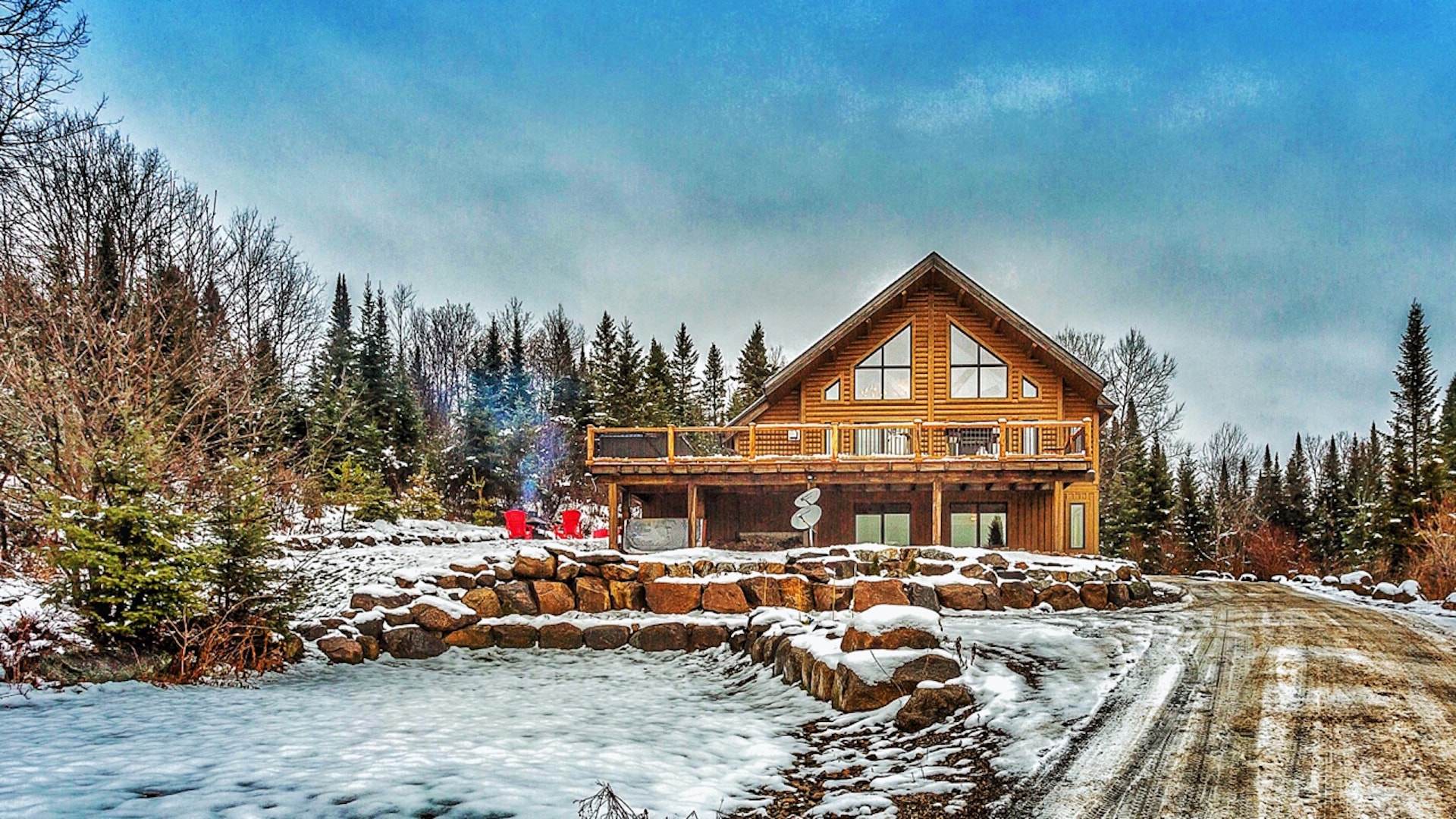 Chalet entouré d'arbres et d'un ruisseau en hiver.